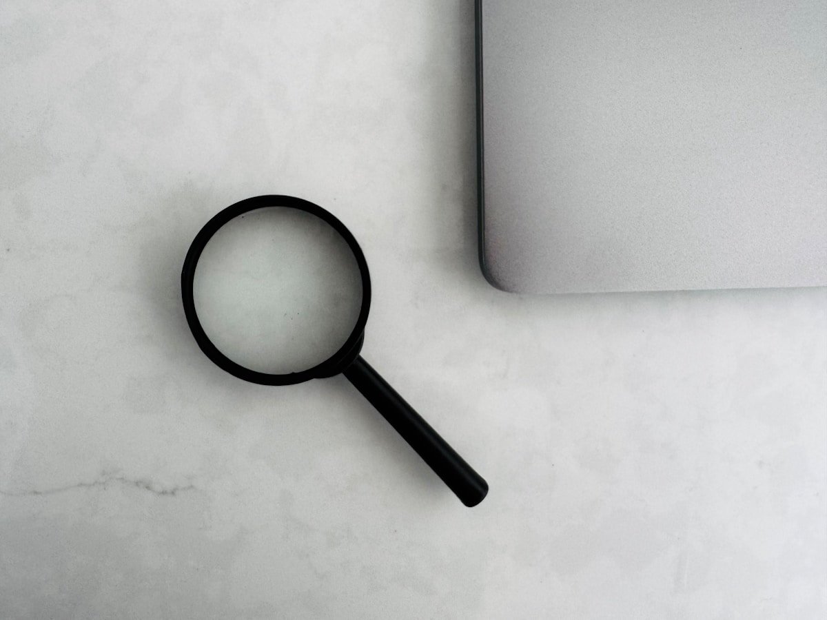 Magnifying glass sits near a laptop on a table.